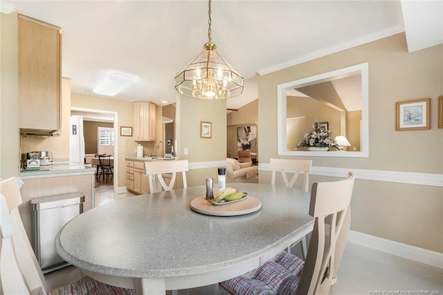 dining area with sink, an inviting chandelier, crown molding, lofted ceiling, and light tile patterned floors