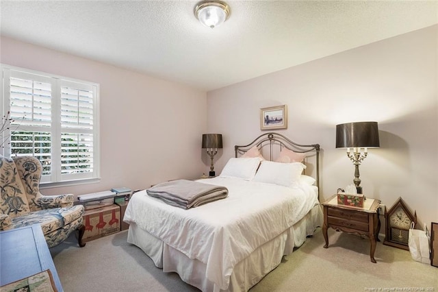 bedroom featuring light carpet and a textured ceiling