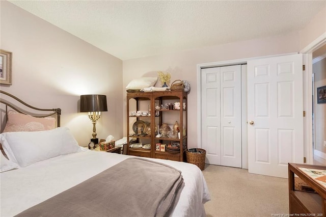 bedroom with a textured ceiling, light colored carpet, and a closet