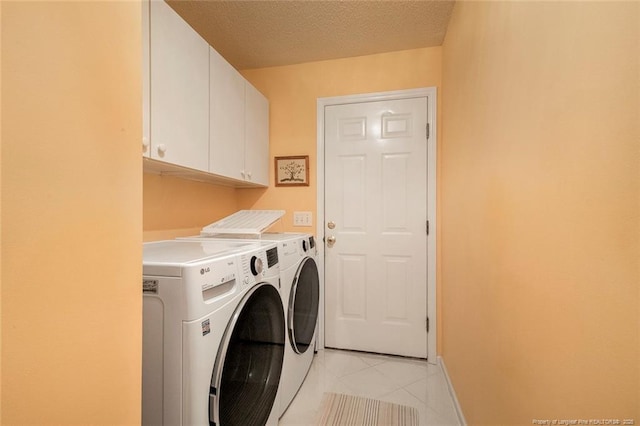 clothes washing area featuring cabinets, independent washer and dryer, a textured ceiling, and light tile patterned floors