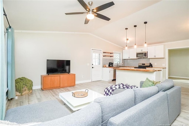 living room with ceiling fan, crown molding, sink, light hardwood / wood-style floors, and lofted ceiling