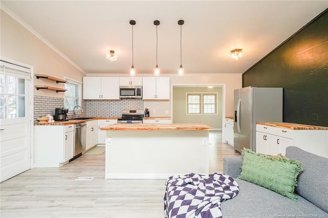 kitchen featuring pendant lighting, sink, a kitchen island, white cabinetry, and stainless steel appliances