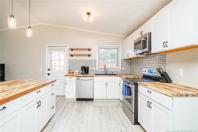 kitchen with wooden counters, pendant lighting, stainless steel appliances, and white cabinetry