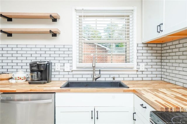 kitchen featuring white cabinetry, decorative backsplash, stainless steel appliances, and wood counters