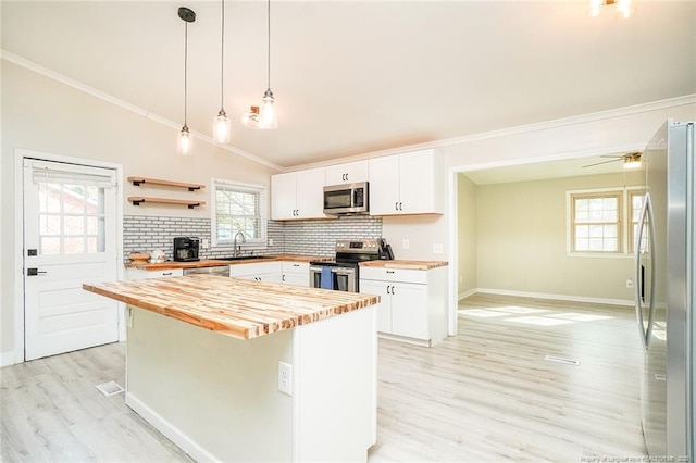 kitchen with white cabinets, wood counters, a kitchen island, and appliances with stainless steel finishes