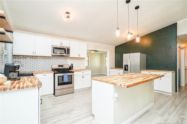 kitchen featuring appliances with stainless steel finishes, butcher block countertops, white cabinetry, and a kitchen island