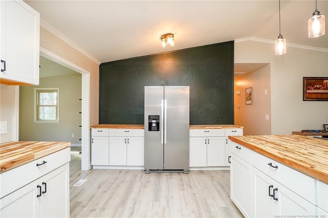 kitchen featuring white cabinets, stainless steel fridge, butcher block countertops, and hanging light fixtures