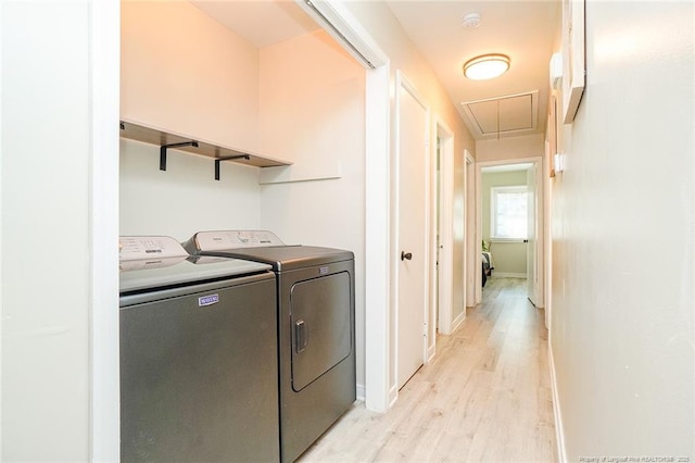 laundry room with washing machine and clothes dryer and light hardwood / wood-style floors