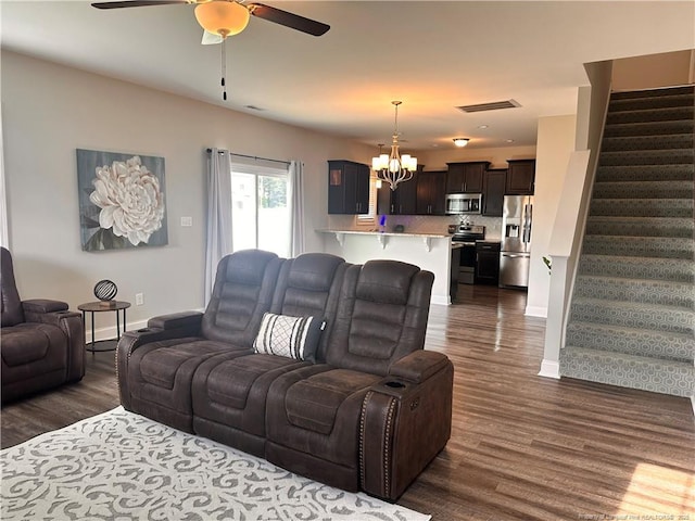 living room featuring ceiling fan with notable chandelier and dark hardwood / wood-style flooring