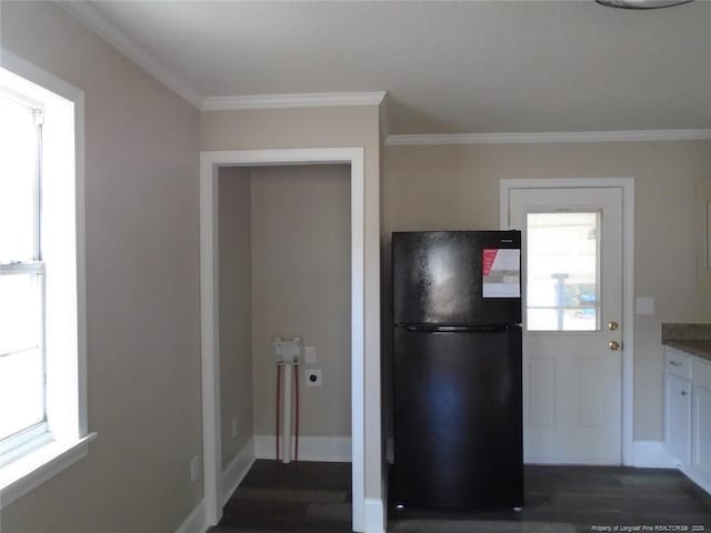 kitchen featuring black refrigerator, white cabinetry, ornamental molding, and a wealth of natural light