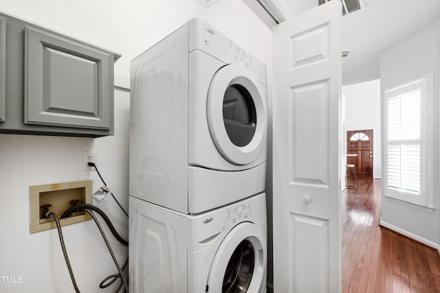 laundry area featuring stacked washer and dryer and dark wood-type flooring