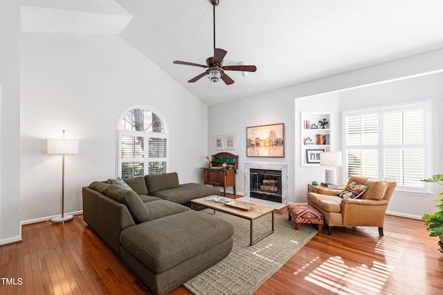 living room featuring built in shelves, high vaulted ceiling, ceiling fan, and hardwood / wood-style flooring