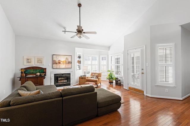 living room with a textured ceiling, lofted ceiling, ceiling fan, hardwood / wood-style flooring, and a premium fireplace