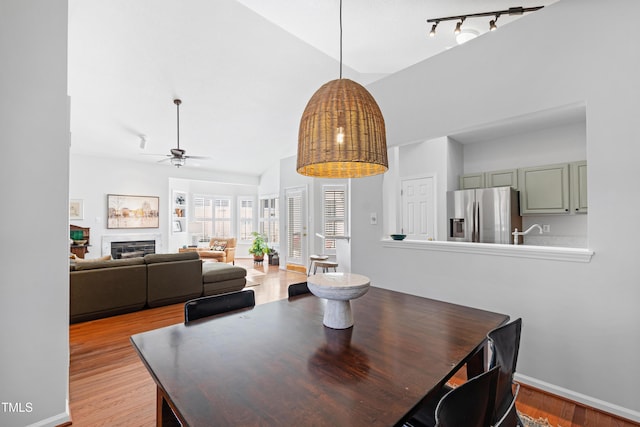 dining space with ceiling fan, light hardwood / wood-style floors, and vaulted ceiling