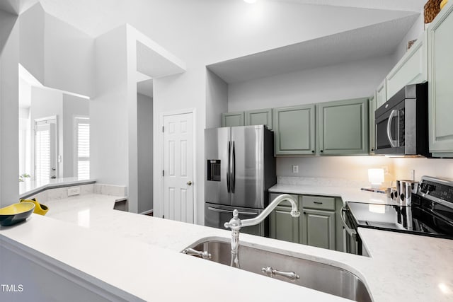 kitchen with stainless steel appliances, green cabinets, sink, and kitchen peninsula