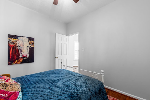 bedroom with a textured ceiling, ceiling fan, and dark wood-type flooring