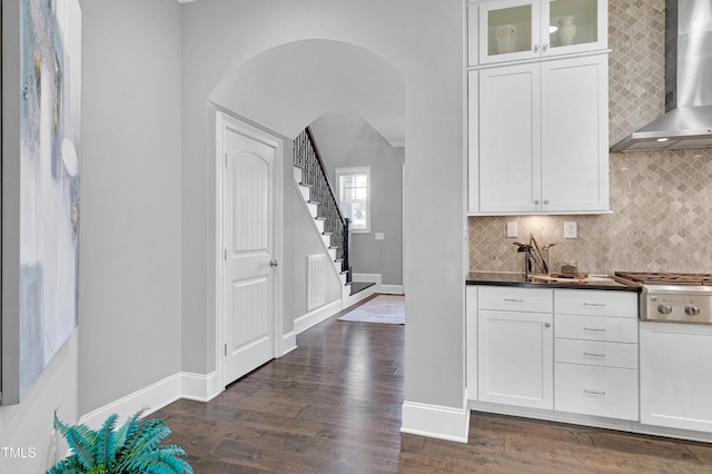 kitchen featuring white cabinets, tasteful backsplash, stainless steel gas cooktop, and wall chimney exhaust hood