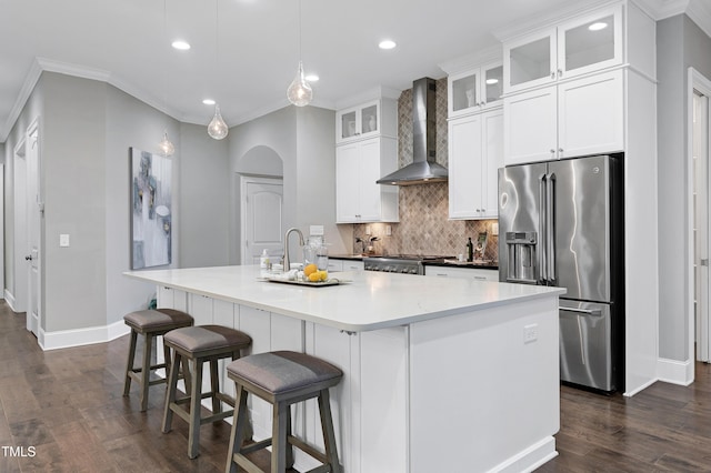 kitchen featuring white cabinetry, a center island with sink, wall chimney exhaust hood, and high end refrigerator