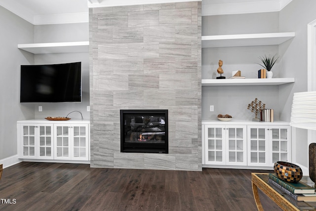 unfurnished living room featuring a tiled fireplace, crown molding, and dark hardwood / wood-style flooring