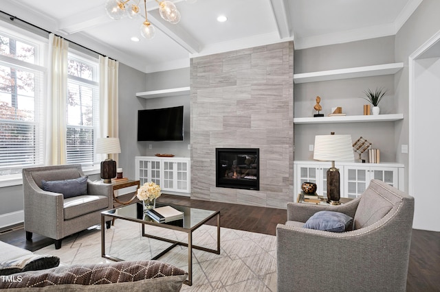 living room with beam ceiling, light hardwood / wood-style floors, a tiled fireplace, and built in shelves