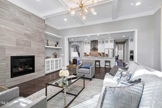 living room featuring beam ceiling, built in shelves, an inviting chandelier, light hardwood / wood-style floors, and a fireplace