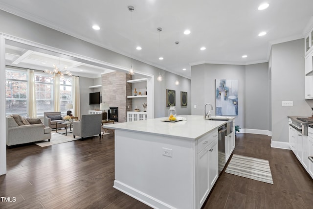 kitchen with white cabinets, sink, a center island with sink, and a fireplace