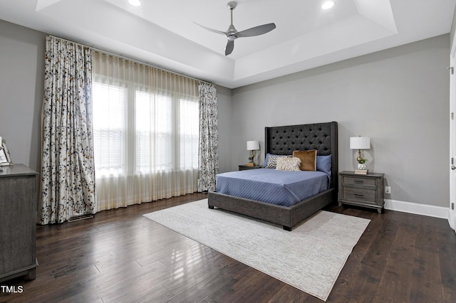 bedroom featuring ceiling fan, dark hardwood / wood-style flooring, and a raised ceiling