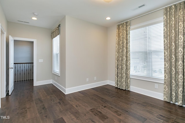 empty room with a healthy amount of sunlight and dark hardwood / wood-style floors