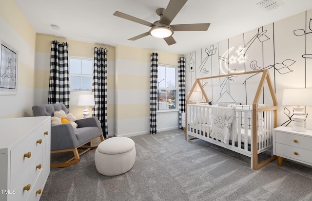 bedroom with ceiling fan, a crib, and carpet