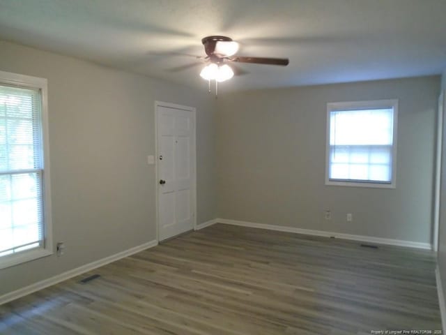 unfurnished room featuring ceiling fan, plenty of natural light, and dark wood-type flooring