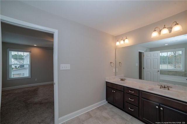 bathroom featuring vanity, a healthy amount of sunlight, and a tub to relax in