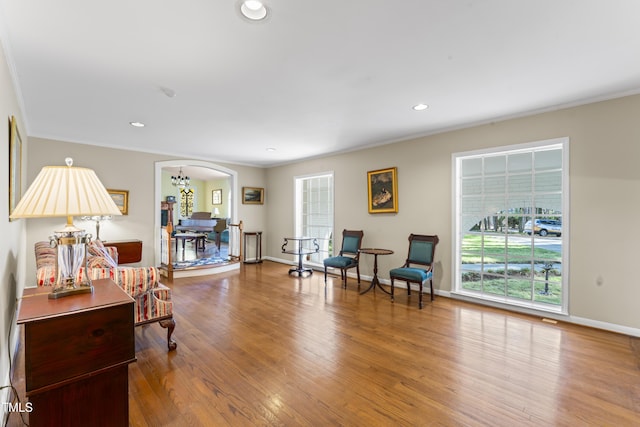 living area featuring hardwood / wood-style flooring, ornamental molding, and an inviting chandelier