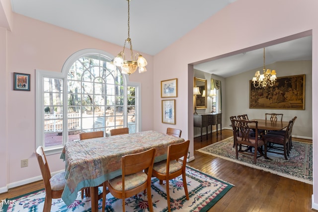 dining area featuring dark wood-type flooring, a chandelier, and vaulted ceiling