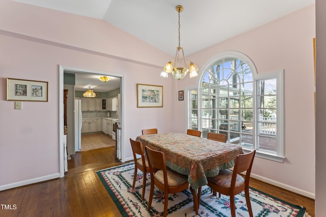 dining area with vaulted ceiling, dark wood-type flooring, and a chandelier