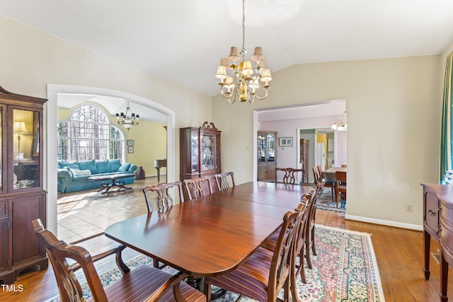 dining room featuring an inviting chandelier, lofted ceiling, and light wood-type flooring