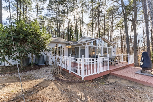 view of front of property with a wooden deck, a sunroom, and a fire pit