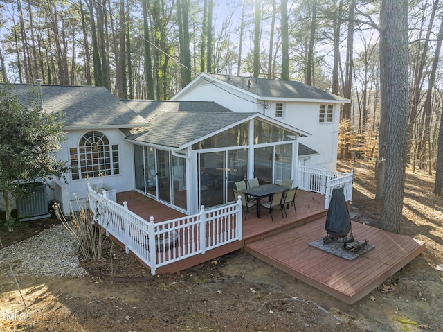 rear view of house with central AC unit, a sunroom, and a deck