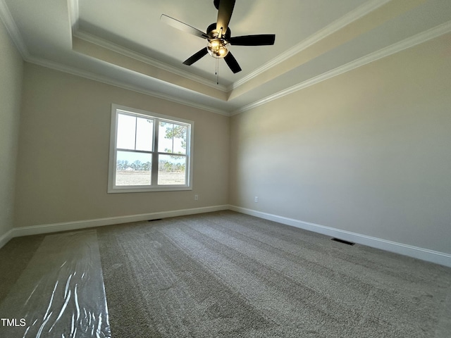 carpeted spare room with baseboards, visible vents, a tray ceiling, and ornamental molding