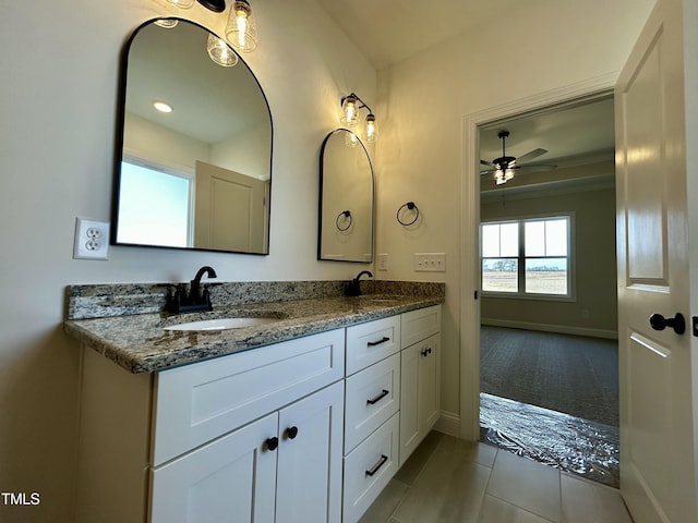 full bath with double vanity, tile patterned flooring, a sink, and baseboards