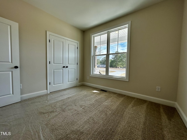 unfurnished bedroom featuring light carpet, visible vents, and baseboards