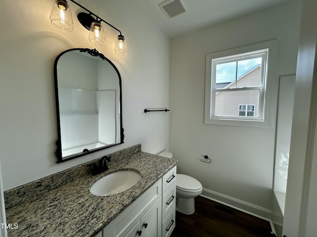 bathroom featuring baseboards, visible vents, toilet, wood finished floors, and vanity