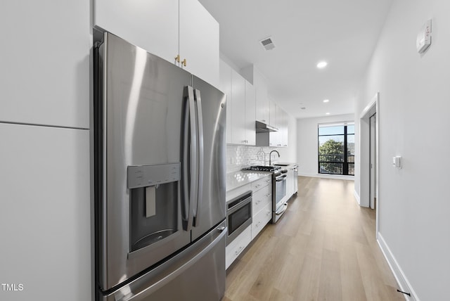 kitchen with sink, white cabinetry, backsplash, stainless steel appliances, and light hardwood / wood-style floors