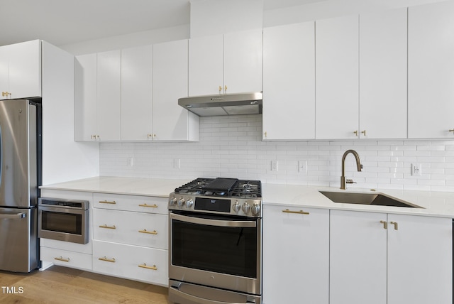 kitchen featuring tasteful backsplash, sink, white cabinets, stainless steel appliances, and light wood-type flooring