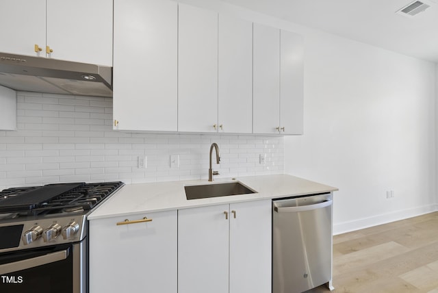 kitchen with sink, light wood-type flooring, stainless steel appliances, decorative backsplash, and white cabinets