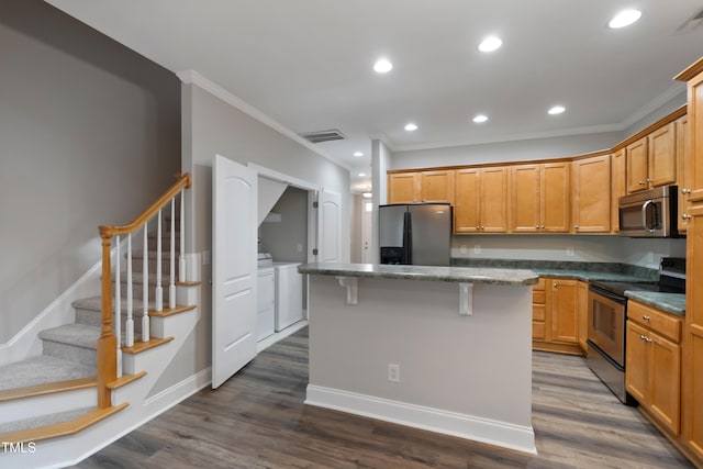 kitchen featuring stainless steel appliances, a center island, dark hardwood / wood-style floors, washing machine and dryer, and crown molding