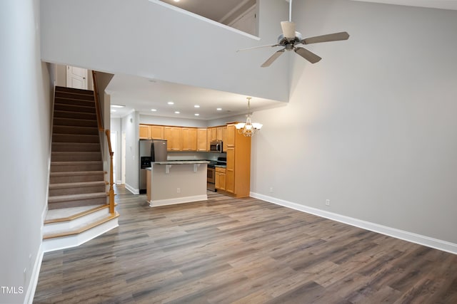 unfurnished living room featuring light hardwood / wood-style floors, ceiling fan with notable chandelier, and a high ceiling