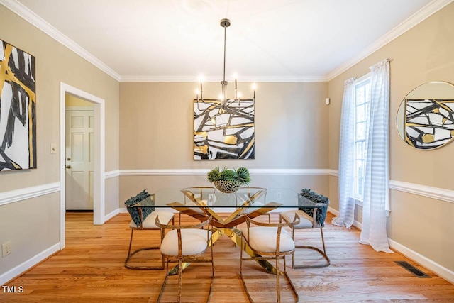 dining area with light hardwood / wood-style floors, crown molding, and a chandelier