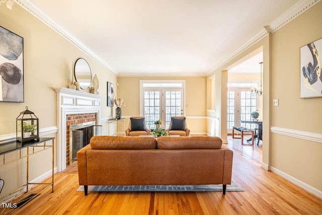 living room with light hardwood / wood-style floors, a brick fireplace, a chandelier, and a wealth of natural light