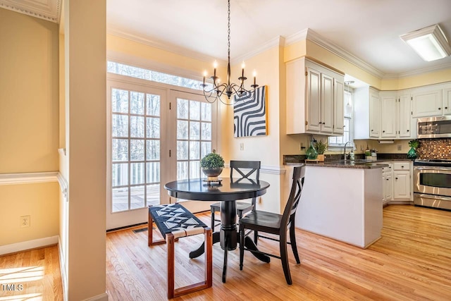 dining area with ornamental molding, light wood-type flooring, an inviting chandelier, and plenty of natural light