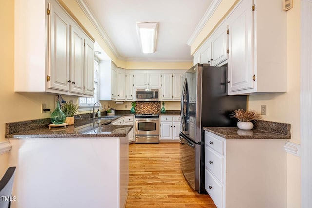 kitchen featuring stainless steel appliances, white cabinets, sink, and kitchen peninsula